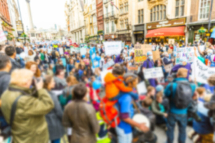 Blurred background of thousands people marching in London streets for a rally. It could be related to politic or social issues.